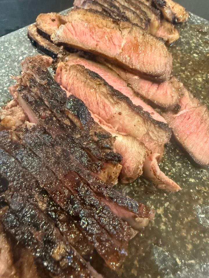 Medium-rare New York strip steak sliced across the grain after cast-iron searing