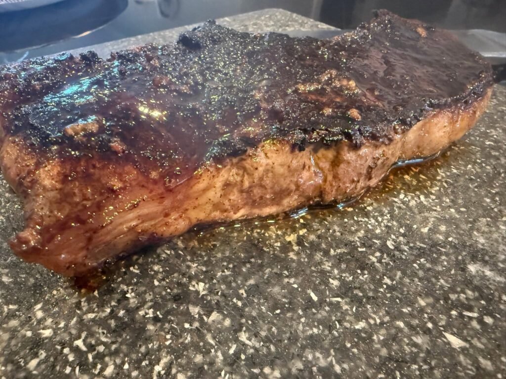 Thick New York strip steak seared in a cast-iron skillet with a dark crust