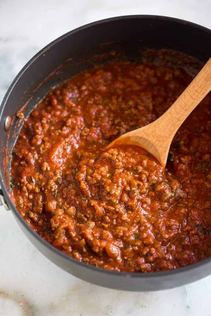 Spaghetti topped with homemade ground beef meat sauce, grated Parmesan, and fresh herbs