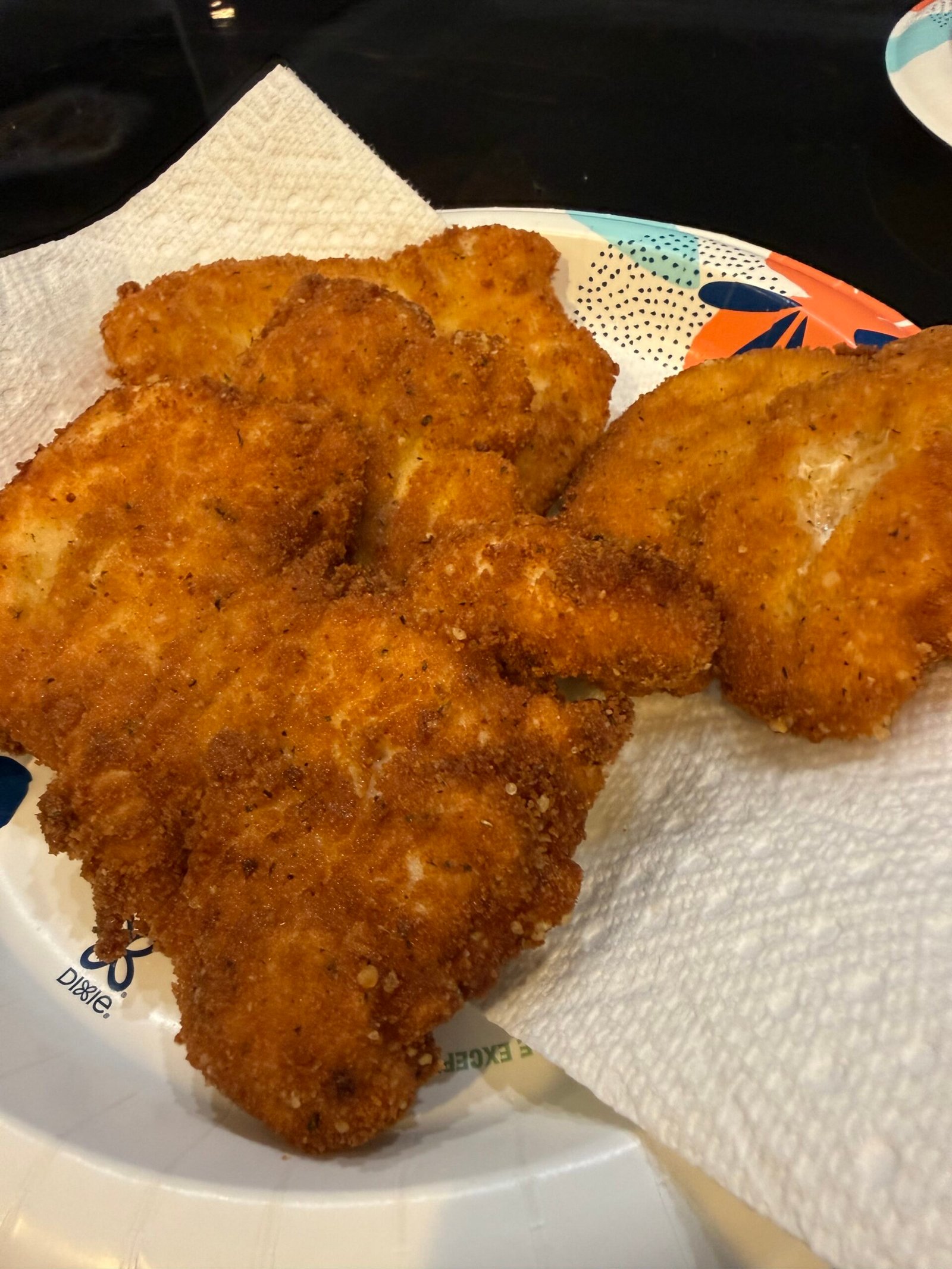 Crispy golden-brown chicken milanesa cutlets resting on a wire rack after frying.